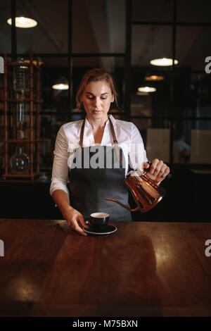 Coffee shop besitzer Kaffee in eine Schale giessen. Frau Kaffee in einem Café. Stockfoto