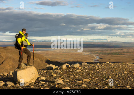 Mann, auf Fels in dramatischen beleuchtete Landschaft Panorama in Island. Blick auf die Kjölur Hochland und Vulkan Hekla. Stockfoto