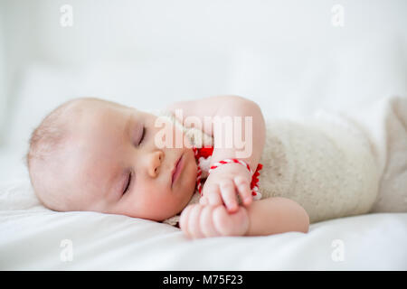 Cute Baby Toddler Boy, Schlafen mit weißen und roten Armband. Martenitsa, weiße und rote Sorten aus Garnen, bulgarischen Folklore Tradition, der Frühling Stockfoto