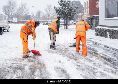 Arbeitnehmer schneeschaufeln von einer Straße in ein Auto Park, West Bridgford, Nottinghamshire, England, Großbritannien Stockfoto