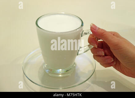 Frau' Hand mit einer Tasse warmen Büffel, serviert in transparentem Glas Schale Stockfoto