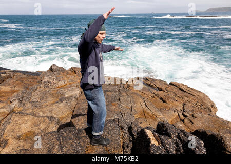 Ein Tourist watching kraftvolle Wellen schlagen Felsen in Cornwall an der Küste von der Keltischen See Stockfoto