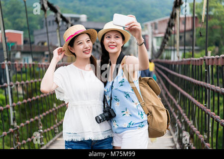 Junge asiatische schöne Backpackers unter selfie auf die hölzerne Hängebrücke jingtong, Taiwan. Im sonnigen Sommertag. Stockfoto
