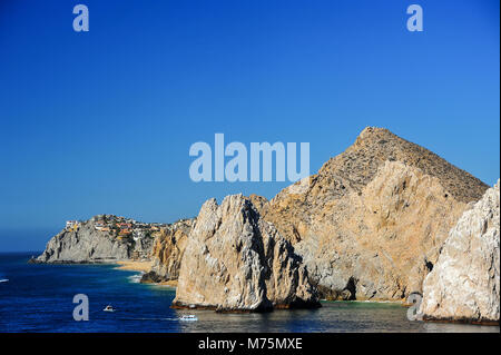 Ansicht vom Meer entlang der felsigen Küste von Cabo San Lucas. Bunte Resort Hotels barsch oben Pedregal Beach durch den klaren, blauen Himmel umrahmt Stockfoto