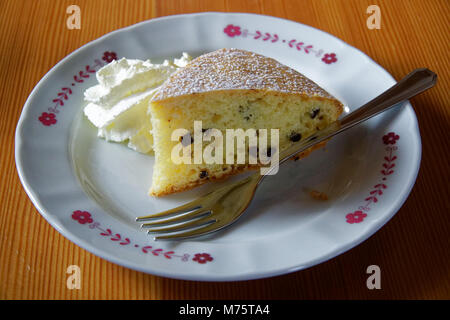 Biskuitteig mit Sauerrahm und Gabel auf weiße Platte auf hölzernen Tisch, essen Hintergrund. Stockfoto