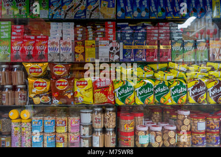 Ein Detail der sortierten Snacks wie Kekse, Chips und anderen Waren, die auf Regalen in einer Ecke Shop (Convenience Store) Fenster auf Gerrard Street, Chinatown, am 5. März 2018 in London, England. Stockfoto