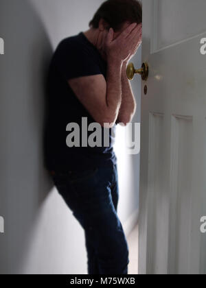 Mann mit Kopf in den Händen, die in der Tür gedrückt Stockfoto