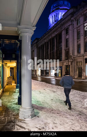 Ein Mann auf einer Straße der Stadt in der Nacht mit Schnee auf dem Boden liegend im Winter, Nottingham, England, Großbritannien Stockfoto