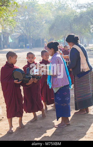 Prozession der buddhistischen Mönche sammeln Almosen in Bagan, Myanmar (Burma), Asien im Februar - lokale Frauen geben Reis und Nahrung Stockfoto