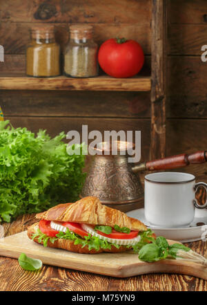Das traditionelle Frühstück. Croissant Sandwich mit Tomaten, Käse, Salat und Basilikum. Caprese. Selektiver Fokus Stockfoto