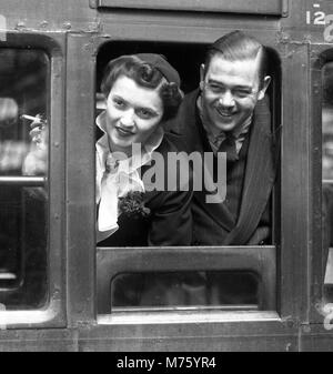 Flitterwochen-Paar, das mit dem Zug von Waterloo Station, London 1945, abreist Stockfoto