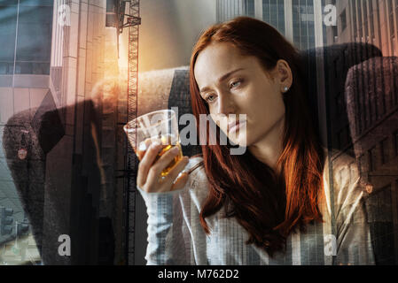 Erschöpft gedrückt Frau alleine saßen und am Glas Alkohol Stockfoto