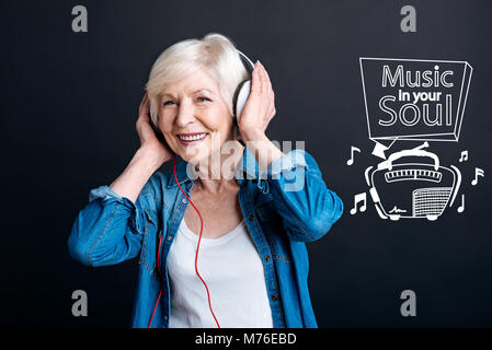 Heiter, reife Frau lächelnd, während Sie Musik hören Stockfoto
