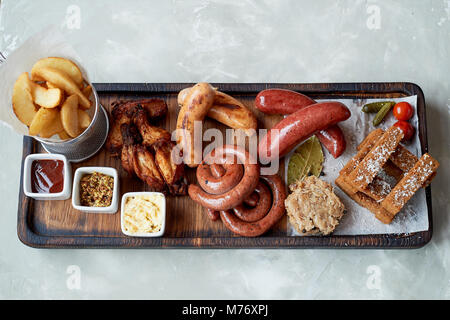 Fleisch für ein großes Unternehmen, das auf einem Holzständer. Gegrillte Würstchen, Sauerkraut, Pommes frites und Saucen. Ansicht von oben Stockfoto
