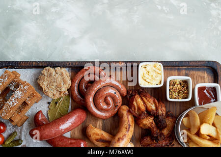 Fleisch für ein großes Unternehmen, das auf einem Holzständer. Gegrillte Würstchen, Sauerkraut, Pommes frites und Saucen. Ansicht von oben Stockfoto