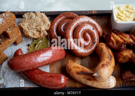 Fleisch für ein großes Unternehmen, das auf einem Holzständer. Gegrillte Würstchen, Sauerkraut, Pommes frites und Saucen. Ansicht von oben Stockfoto