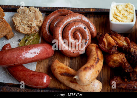 Fleisch für ein großes Unternehmen, das auf einem Holzständer. Gegrillte Würstchen, Sauerkraut, Pommes frites und Saucen. Ansicht von oben Stockfoto