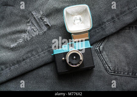 Kompakte vintage plastic film Kamera mit Blitz auf dunkelgrau Jeans Stoff von einem hohen Winkel anzeigen Stockfoto