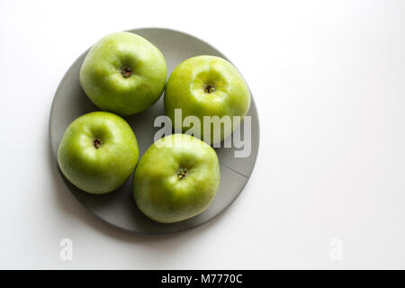Vier Reifen grüne Äpfel auf grauem Beton Platte aus einem hohen Winkel anzeigen isoliert Stockfoto