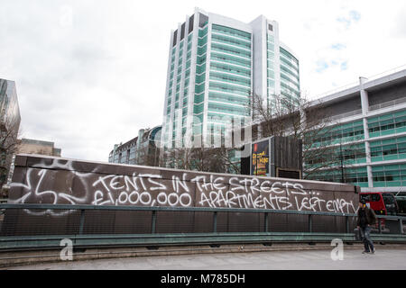 London, Großbritannien. 8. März, 2018. Ein Mann blickt auf Graffiti referenzieren die Gegenüberstellung zwischen Obdachlose leben in Zelten auf den Straßen und £ 1 m Luxury Apartments verbleibenden leeren. Credit: Mark Kerrison/Alamy leben Nachrichten Stockfoto