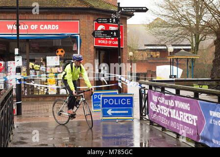 Salisbury, Wiltshire, Großbritannien, 9.. März 2018. Das Einkaufszentrum Maltings, Schauplatz eines Nervengasangriffs auf den ehemaligen russischen Spion Sergei Skripal und seine Tochter, bei dem das Paar auf einer Bank zusammenbrach, bleibt hinter einer Polizeikordel. Ein vorbeifahrender Radfahrer schaut zu. Stockfoto