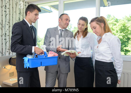 Auszubildende, die Reinigung eines Spiegels unter Aufsicht Stockfoto