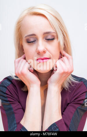 Entspannung und Meditation Techniken. Junge blonde Frau mit geschlossenen Augen die Ohrläppchen mit den Fingern. Stockfoto
