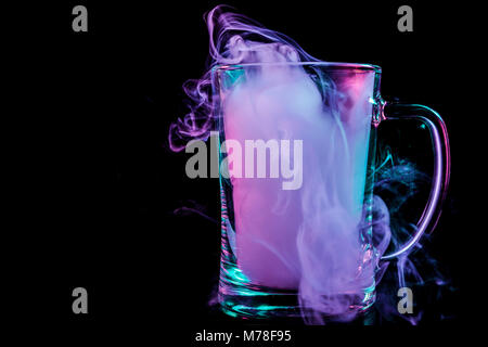 Ein Glas transparent Bier Glas mit einer Perücke aus einem Blau, Blau, Lila wischen gefüllt raucht und steht auf einem schwarzen Hintergrund isoliert Stockfoto