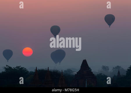 Heißluftballons über Tempel bei Sonnenaufgang an der gemauerten Damm in der Nähe von Taungbi Dorf in Bagan, Myanmar (Birma), Asien im Februar Stockfoto