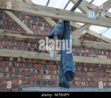 Verblasst und abgenutzte blaue Jeans hängen von den Dachsparren auf einer Baustelle Bild im Querformat mit Kopie Raum Stockfoto