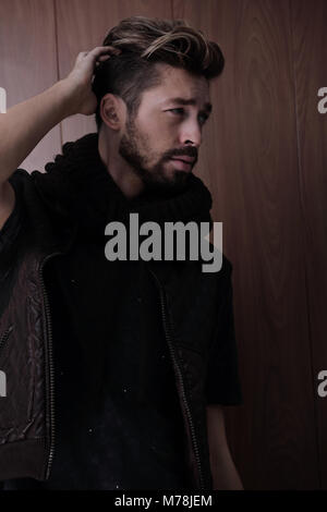 Zornigen Mann ziehen vor den Toren seiner Lederjacke gegen die studio Hintergrund Stockfoto