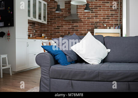 Graue Sofa mit Kissen innerhalb der modernen Apartments Stockfoto