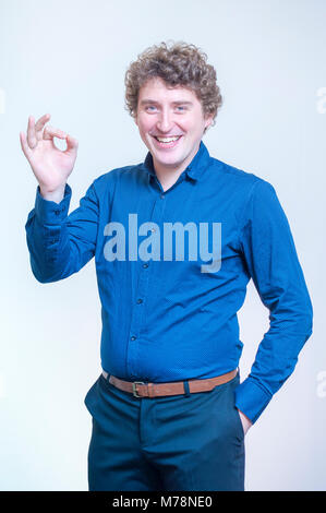 Porträt der jungen kaukasischen Ethnie lustig curly Mann zeigen, O.K. mit Fingern auf weißem Hintergrund. Stockfoto