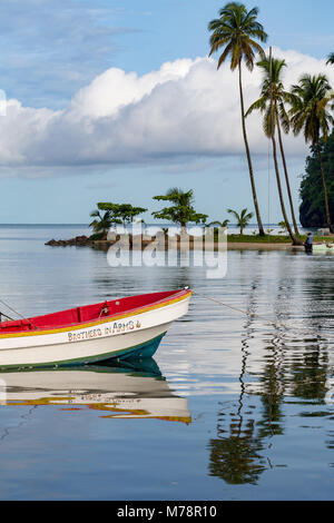 Traditionellen Fischerboot günstig in Marigot Bay mit hohen Palmen am kleinen Strand in der Ferne, St. Lucia, Windward Inseln, Mittelamerika Stockfoto