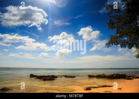 Flache transparent gelb steinigen Meeresgrund unter Ebbe gegen azurblauen Meer und blauen bewölkten Himmel Stockfoto