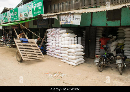 Ein Anbieter in Nyaung U Markt verkaufen Säcke Reis oder Mehl. Die burmesische Mann mit behelfsmäßigen Holz Karre mit Auto Reifen und Räder. Bagan, Myanmar, Birma Stockfoto