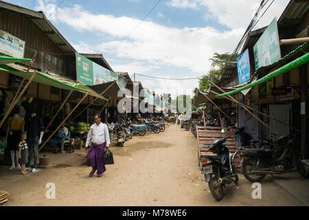 Die burmesische Mann zu Fuß durch pflanzliche und Mode stände im lokalen traditionellen asiatischen Nyaung U Markt Bagan Myanmar Birma, tragen lila longyi Stockfoto