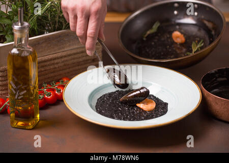 Küchenchef Meeresfrüchte, Muscheln, Garnelen nach Pinzette Essen in eine weiße Platte Stockfoto