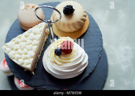 Kuchen auf dunklem Schiefer Etagenbett stehen. Desserts. Süße Tabelle Stockfoto