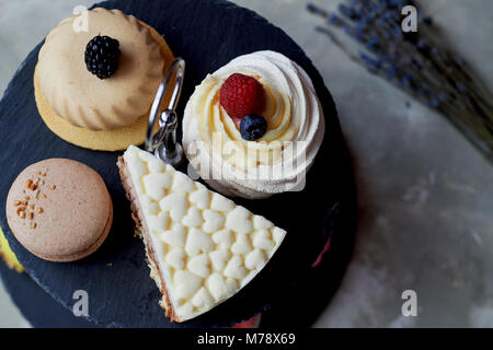 Kuchen auf dunklem Schiefer Etagenbett stehen. Desserts. Süße Tabelle Stockfoto