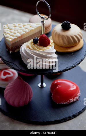 Kuchen auf dunklem Schiefer Etagenbett stehen. Desserts. Süße Tabelle Stockfoto