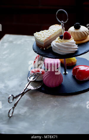 Kuchen auf dunklem Schiefer Etagenbett stehen. Desserts. Süße Tabelle Stockfoto