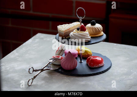 Kuchen auf dunklem Schiefer Etagenbett stehen. Desserts. Süße Tabelle Stockfoto