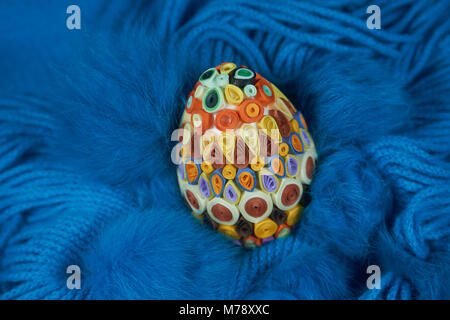 Osterei mit bunten Papier auf einem blauen Wolle Schal dekoriert. Ostern Einrichtung, selektiven Fokus. Stockfoto