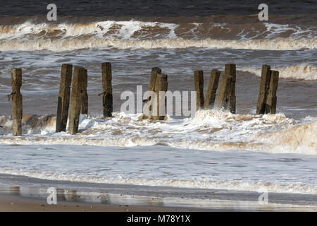 Wellen, die durch gebrochene Deckwerken, Walcott Norfolk Stockfoto