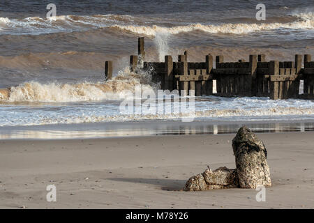 Wellen, die durch gebrochene Deckwerken, Walcott Norfolk Stockfoto