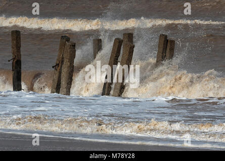 Wellen, die durch gebrochene Deckwerken, Walcott Norfolk Stockfoto