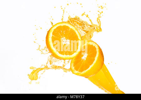 O-Saft spritzt auf halbe Orangen vor einem weißen Hintergrund Stockfoto