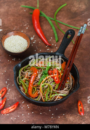 Buchweizen Soba Nudeln mit Karotten, Paprika, Zucchini, Frühlingszwiebeln und Sesam - ein traditionelles Gericht der asiatischen Küche. Vegetarisches Gericht. Selektive Stockfoto