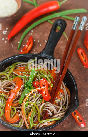 Buchweizen Soba Nudeln mit Karotten, Paprika, Zucchini, Frühlingszwiebeln und Sesam - ein traditionelles Gericht der asiatischen Küche. Vegetarisches Gericht. Selektive Stockfoto